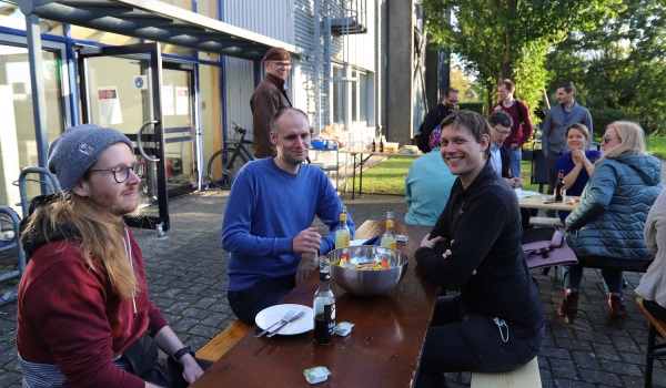 Gäste auf der kleinen Feier am Biertisch sitzend, Hinterhof Campus Sankt Augustin