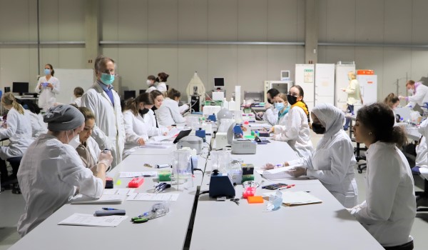 Improvisiertes Labor in einer Halle mit Studierenden und Professor.