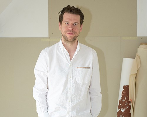 Eine Person steht in einem Atelier und trägt ein weißes Hemd