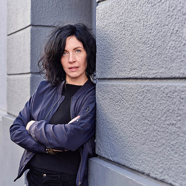 Foto einer Frau, die an einem Hauseingang lehnt