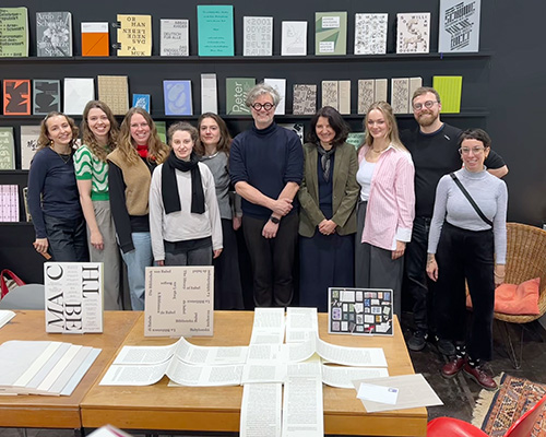 Eine Gruppe Menschen steht vor einem B&uuml;cherregal