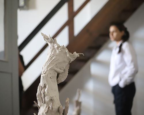 Eine Schülerin schaut sich im Atelier der Künstlerin Nadine Kles um, im Vordergrund steht eine Tonskulptur