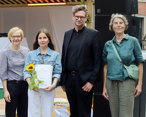 Vier Personen stehen vor einer B&uuml;hne