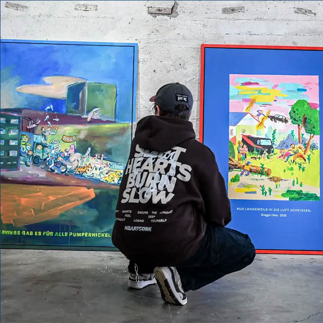 Eine Person kniet vor zwei Bildern und bereitet eine Ausstellung vor