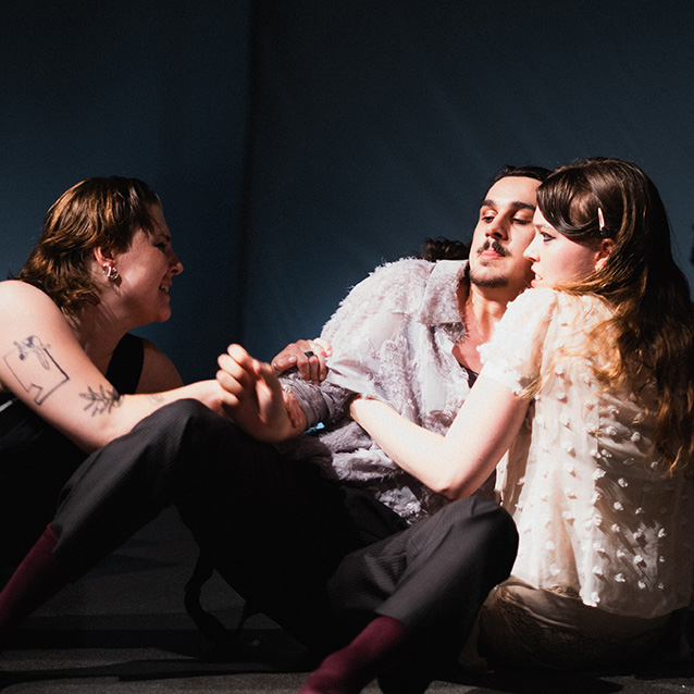 Fotografie einer Theaterprobe, zu sehen sind drei Personen