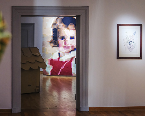 Foto aus einem Ausstellungsraum, in dem M&auml;usefiguren auf St&uuml;hlen sitzen