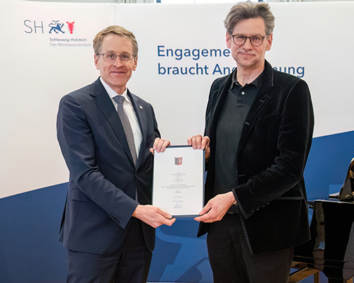 Foto aus einem Ausstellungsraum, in dem M&auml;usefiguren auf St&uuml;hlen sitzen