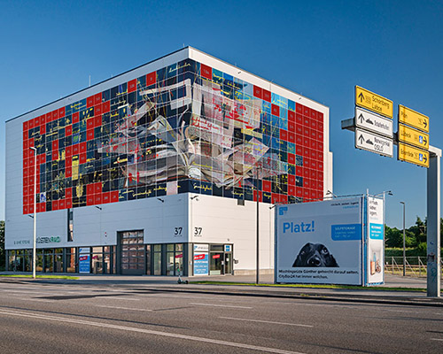 Das Bild zeigt eine Montage der großen Collage "SIGNAL", die an der CityBox24 an der Kieler Bahnhofstraße 37 angebracht wird.